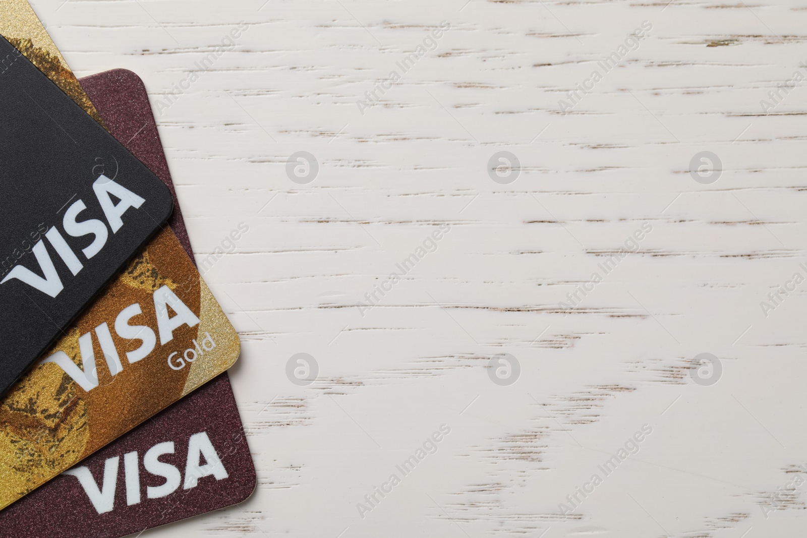 Photo of MYKOLAIV, UKRAINE - FEBRUARY 22, 2022: Visa credit cards on white wooden table, flat lay. Space for text