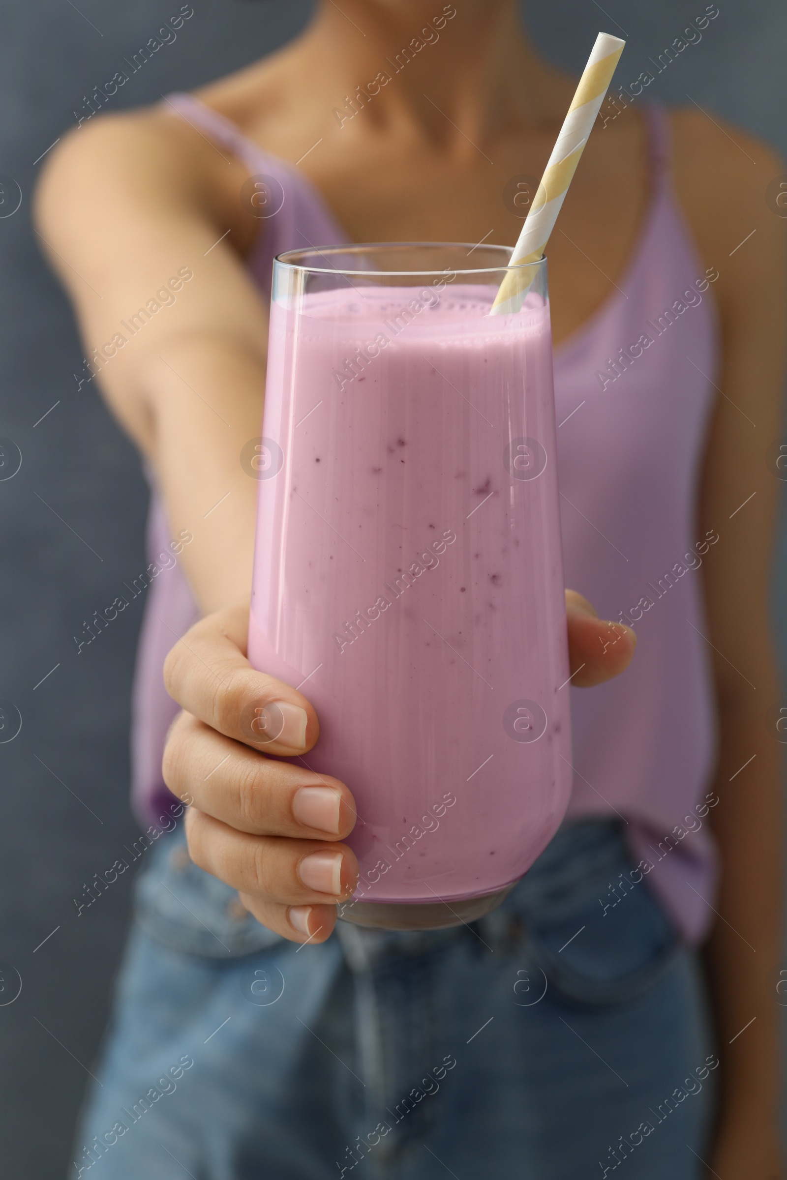 Photo of Woman holding fig smoothie on grey background, closeup