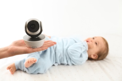 Woman holding baby camera near child on bed. Video nanny