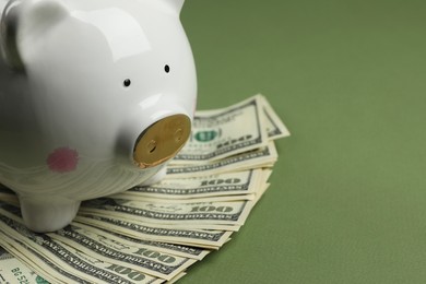 Photo of Money exchange. Dollar banknotes and piggy bank on green background, closeup. Space for text