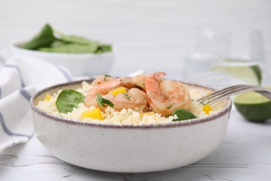 Tasty couscous with shrimps, bell pepper and basil on white textured table, closeup