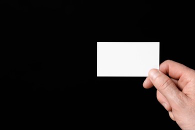 Photo of Man holding blank business card on black background, closeup. Space for text