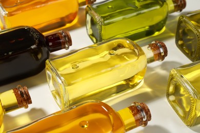 Photo of Vegetable fats. Different cooking oils in glass bottles on white background, closeup