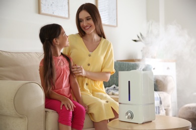 Photo of Mother and daughter near modern air humidifier at home
