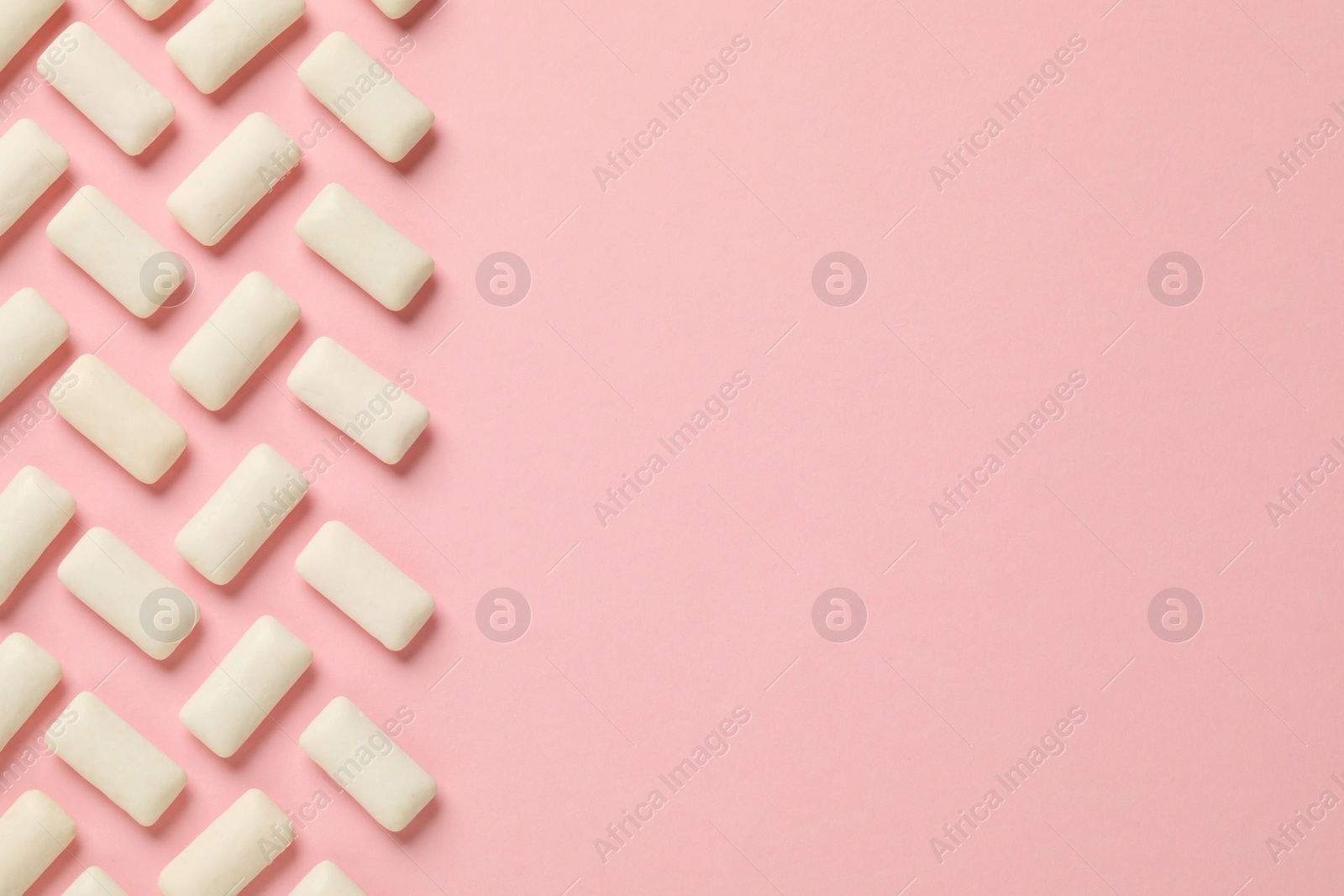 Photo of Many chewing gum pieces on pink background, flat lay. Space for text