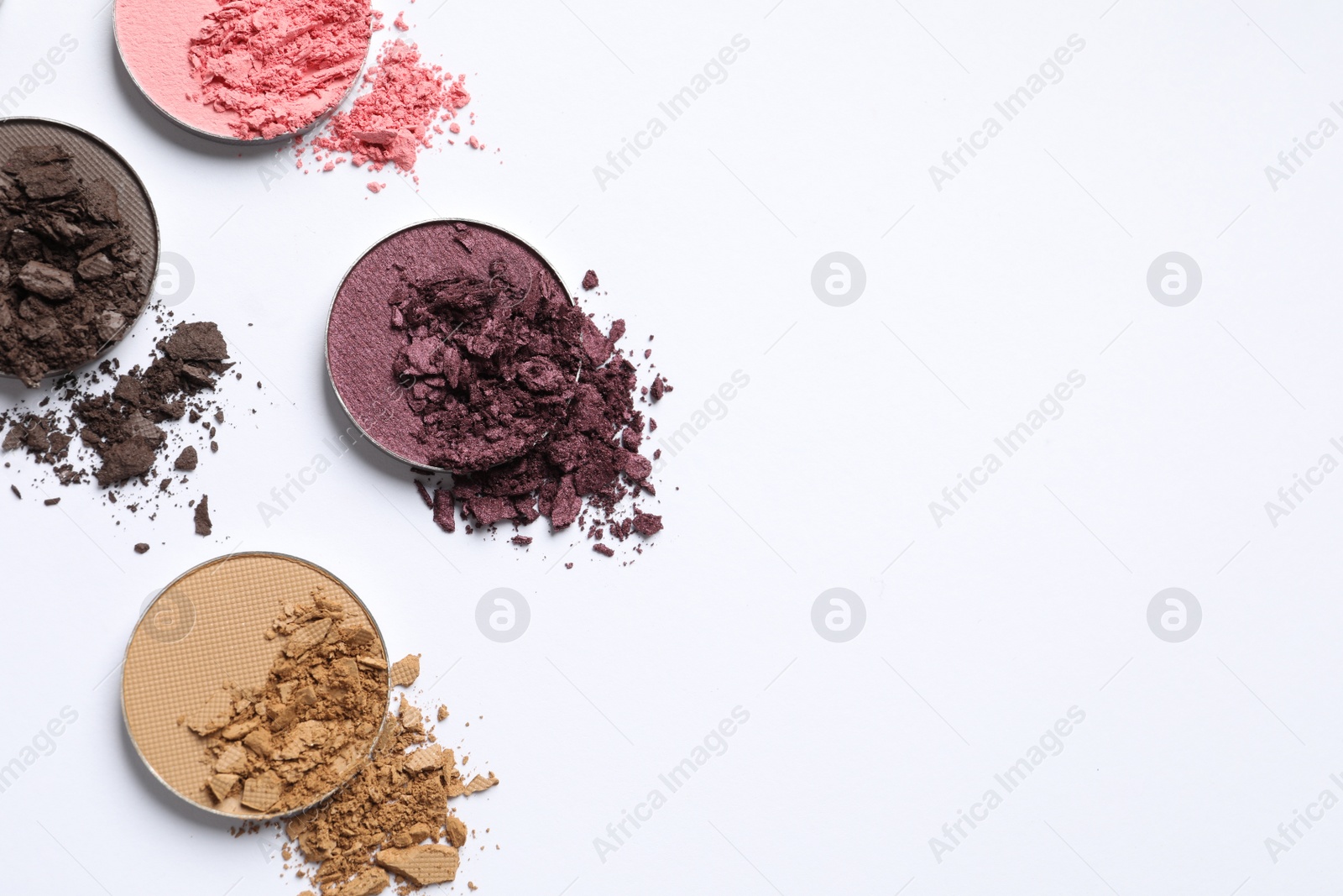 Photo of Different crushed eye shadows on white background, flat lay. Space for text