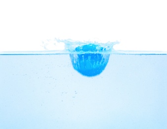 Bath bomb splashing into water on white background