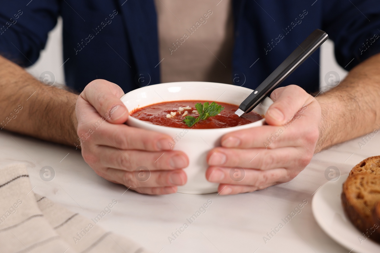 Photo of Man with delicious tomato soup at light table, closeup