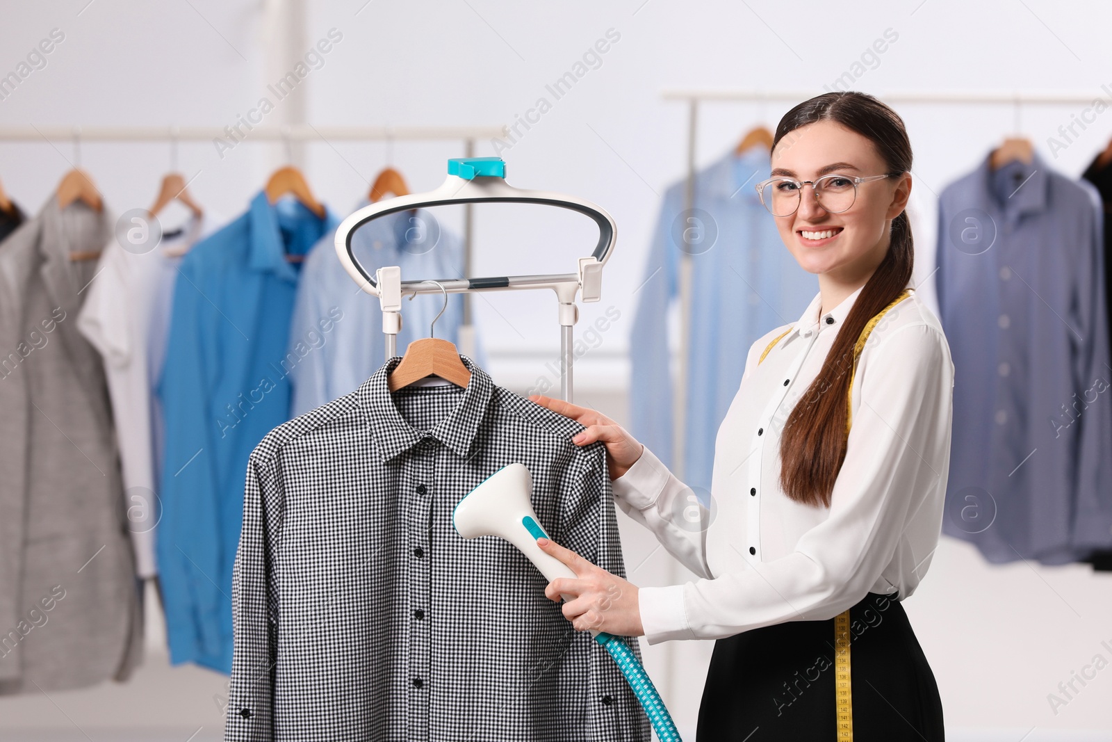 Photo of Woman steaming shirt on hanger in room