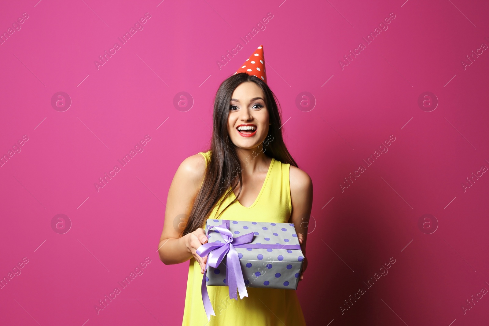 Photo of Young woman with birthday gift on color background