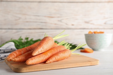 Photo of Cutting board with carrots on table. Space for text