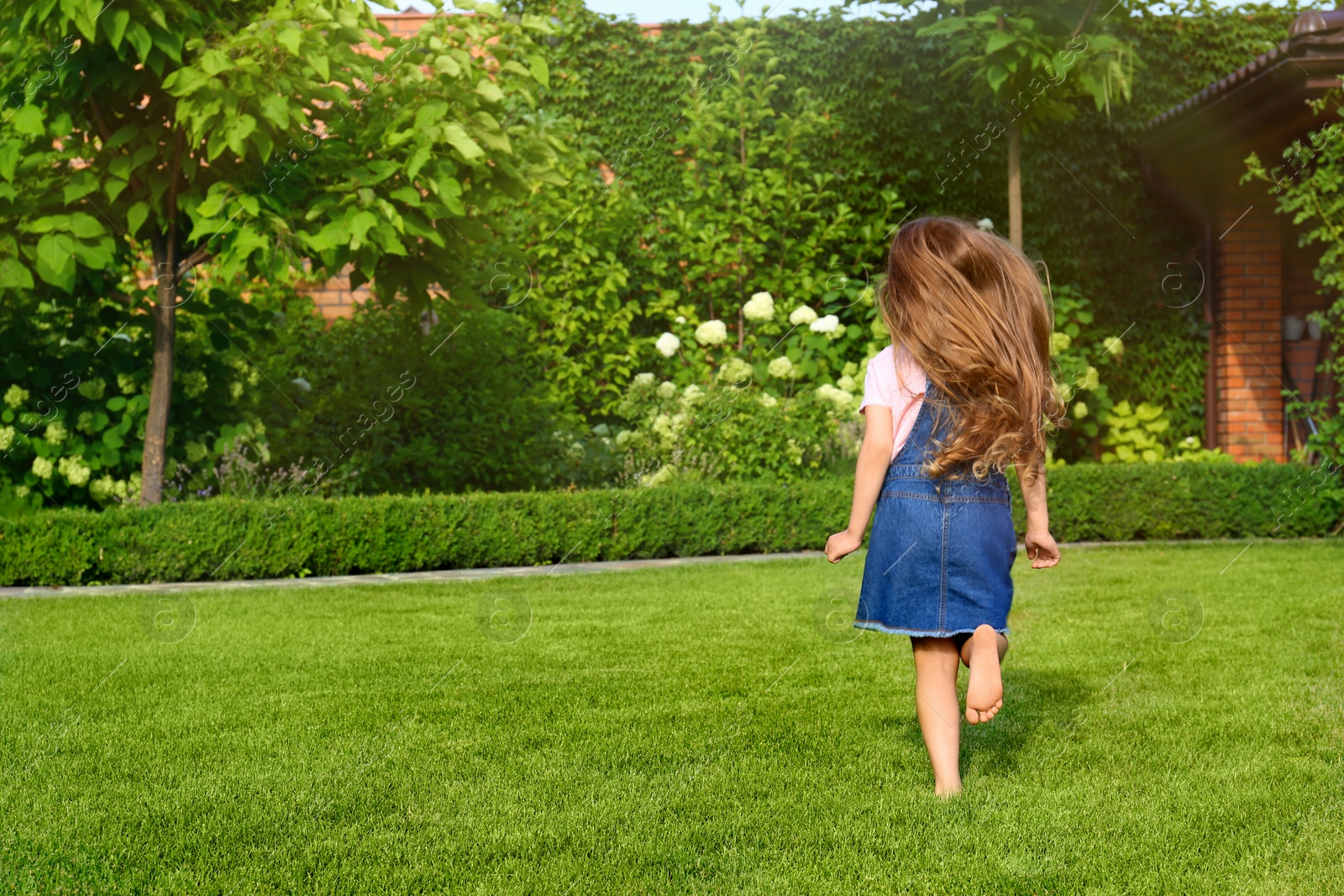 Photo of Cute little girl running in green park on summer day