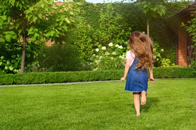 Cute little girl running in green park on summer day