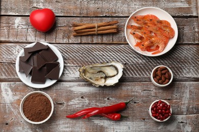 Photo of Natural aphrodisiac. Different food products and heart model on wooden table, flat lay