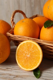 Photo of Many whole and cut oranges on light wooden table, closeup