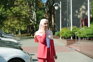 Photo of Muslim woman in hijab talking on phone outdoors