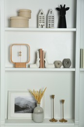 White shelves with books and different decor indoors. Interior design