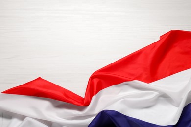 Photo of Flag of Netherlands on white wooden background, top view. Space for text