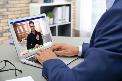 Image of Businessman having video chat with colleague at table, closeup