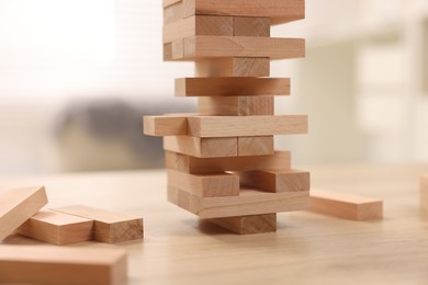 Photo of Jenga tower made of wooden blocks on table indoors, closeup