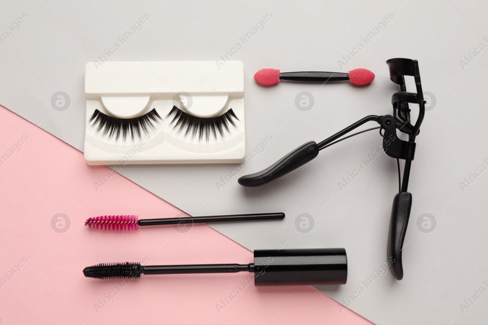 Photo of False eyelashes, curler and brushes on color background, flat lay