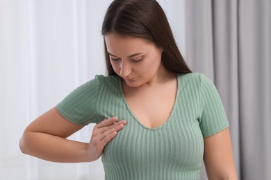 Mammology. Young woman doing breast self-examination indoors