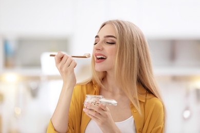 Young woman with yogurt on blurred background