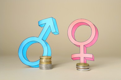 Gender pay gap. Male and female symbols near piles of coins on beige background
