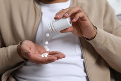 Man pouring antidepressants from bottle onto hand, closeup view