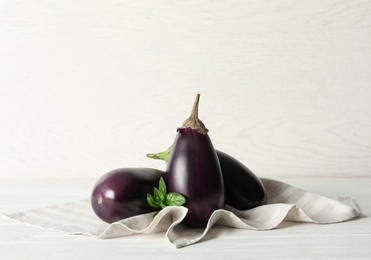 Ripe purple eggplants and basil on white wooden table