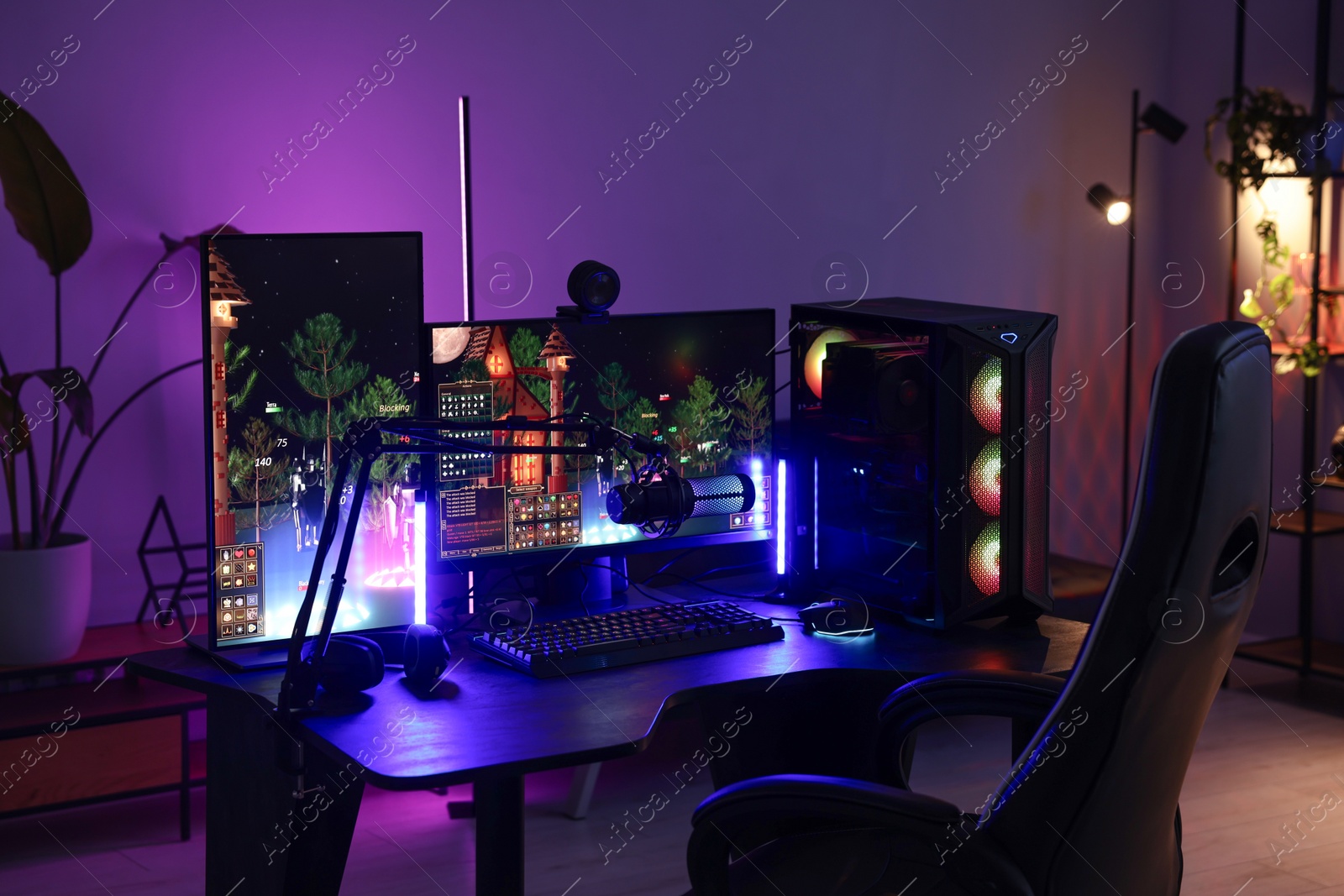 Photo of Playing video games. Stylish room interior with modern computer and gaming chair in neon lights