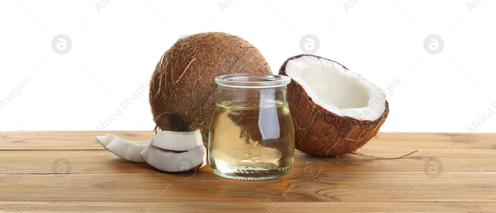 Photo of Ripe coconuts and jar with natural organic oil on wooden table against white background