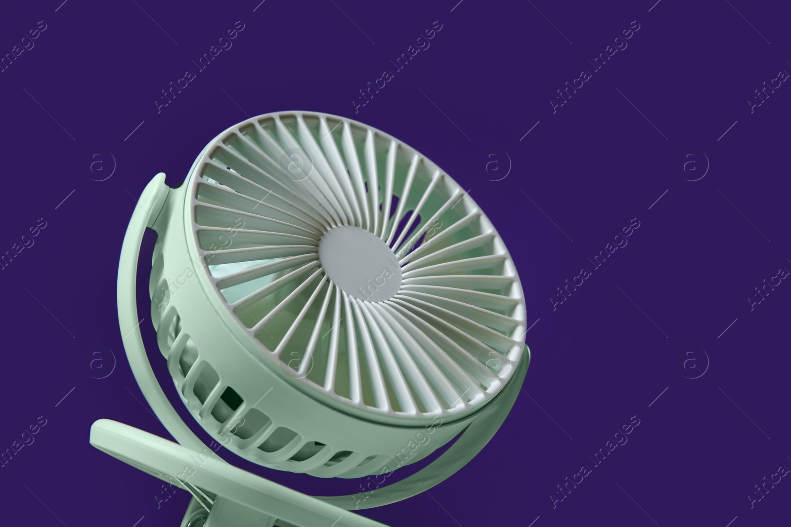 Photo of Modern electric fan on violet background, closeup