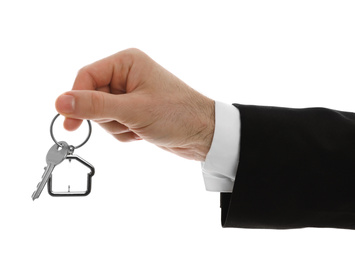 Photo of Real estate agent holding house key with trinket on white background, closeup