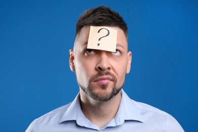 Photo of Emotional man with question mark on blue background