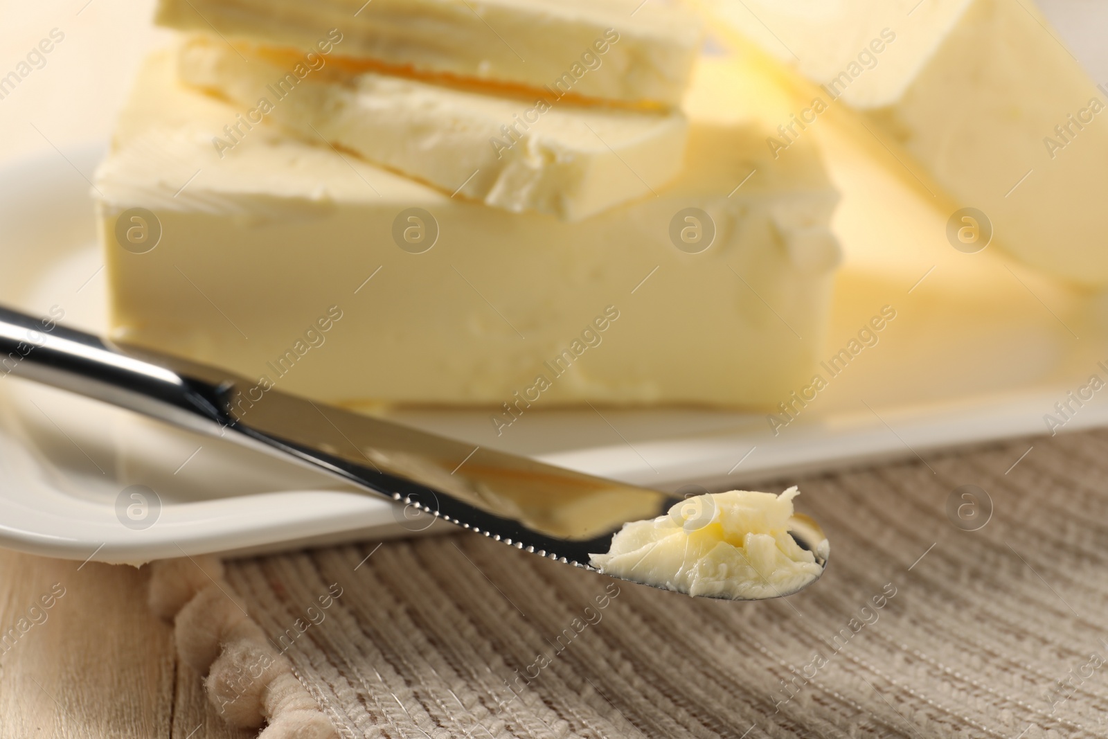 Photo of Tasty butter and knife on wooden table, closeup