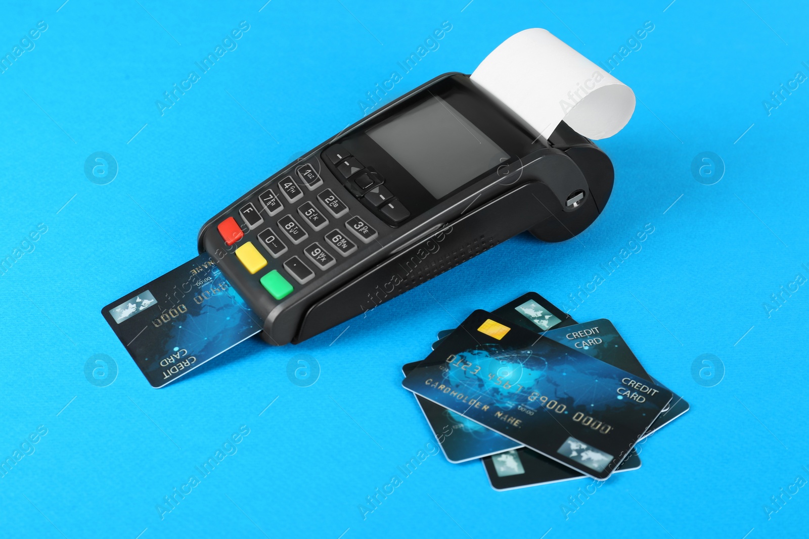 Photo of New modern payment terminal and credit cards on light blue background