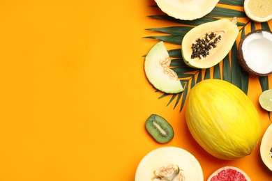 Photo of Flat lay composition with tasty melon and fresh tropical fruits on orange background, space for text