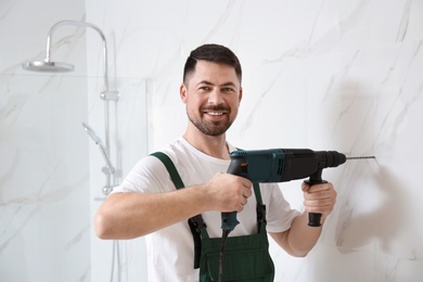 Photo of Handyman working with drill in bathroom. Professional construction tools