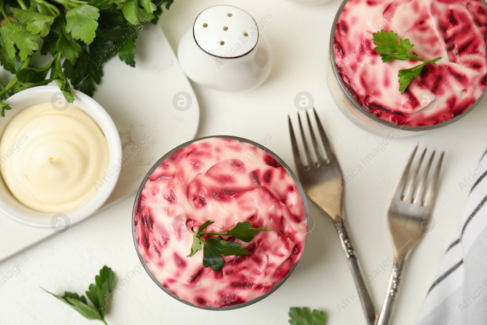 Photo of Herring under fur coat served on white table, flat lay. Traditional russian salad