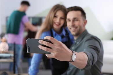 Hairdresser with happy client taking selfie in beauty salon