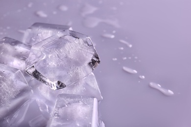 Photo of Transparent ice cubes on color background, closeup. Space for text