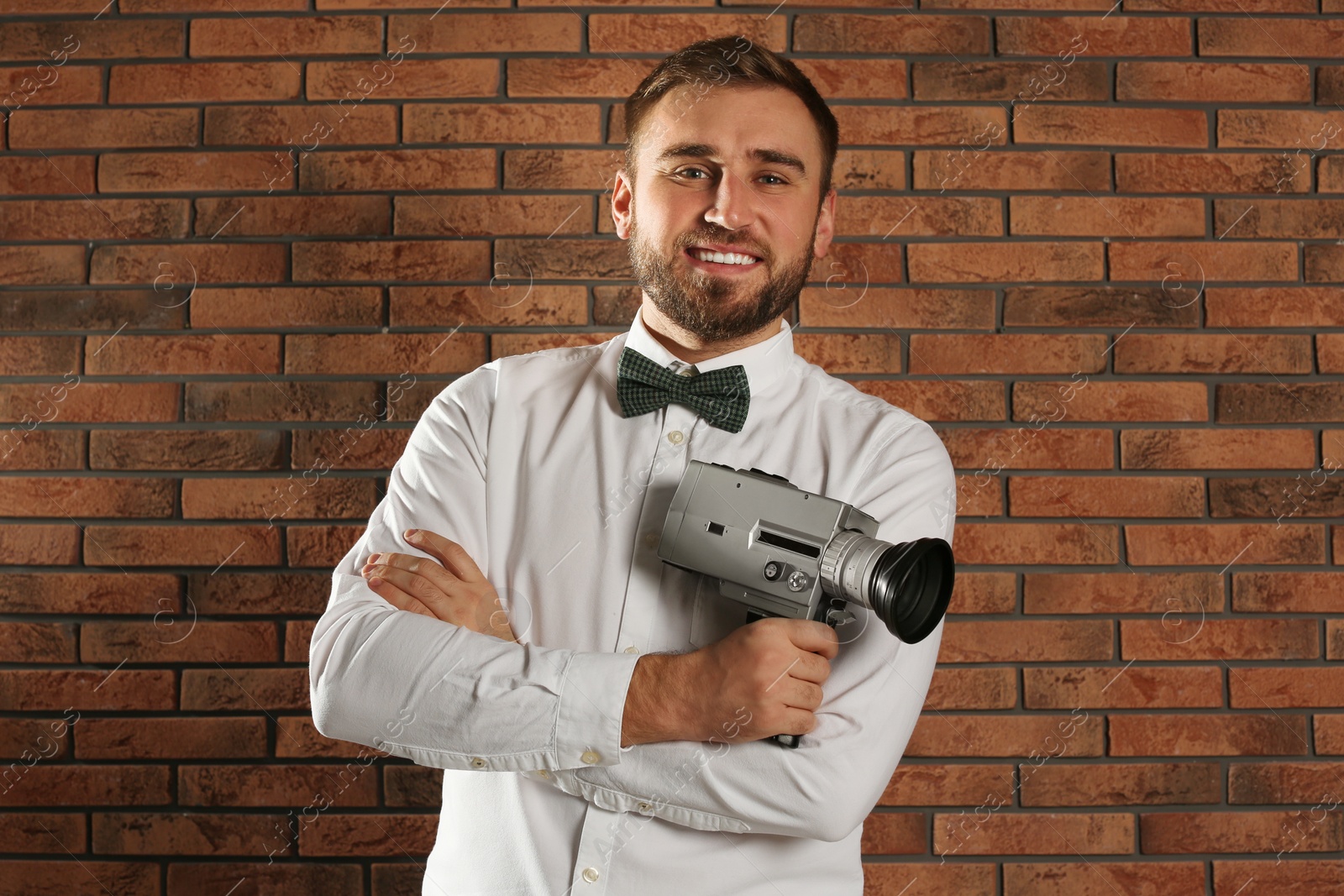 Photo of Young man with vintage video camera near brick wall