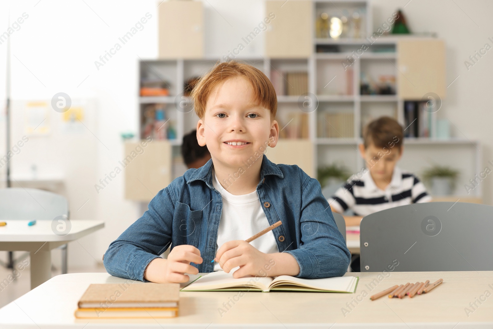 Photo of Portrait of smiling little boy studying in classroom at school