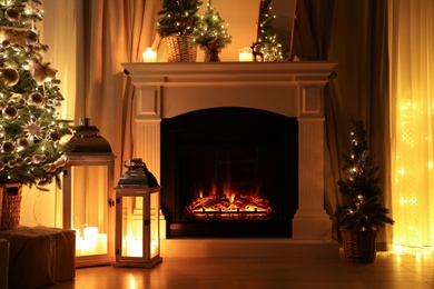 Beautiful fireplace, Christmas tree and other decorations in living room at night. Interior design