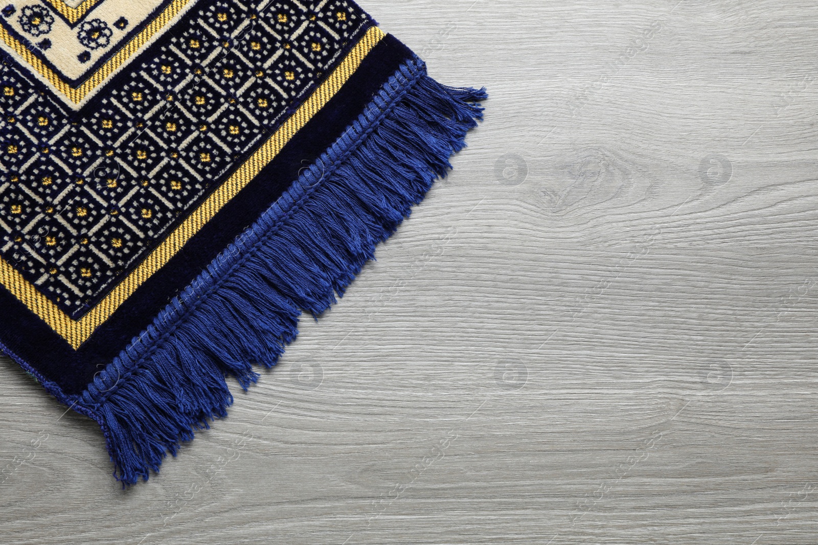 Photo of Muslim prayer rug on wooden table, top view. Space for text