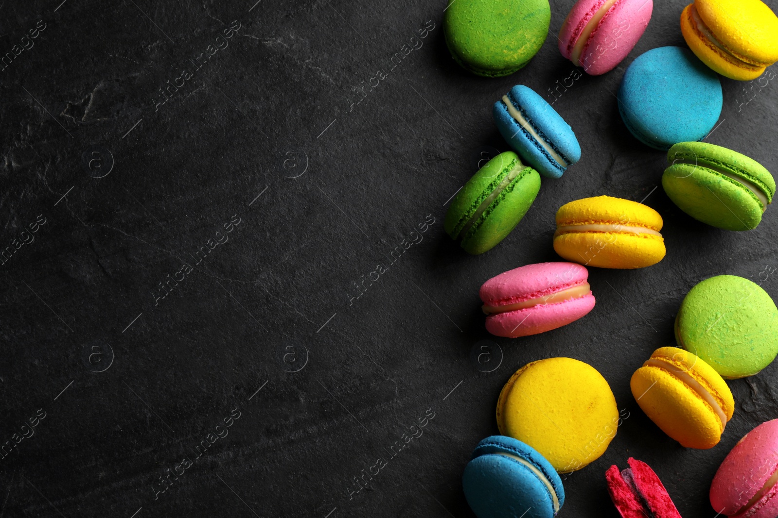 Photo of Delicious colorful macarons on black table, flat lay. Space for text