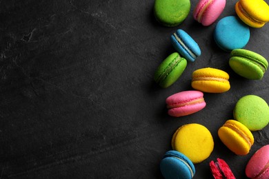 Delicious colorful macarons on black table, flat lay. Space for text