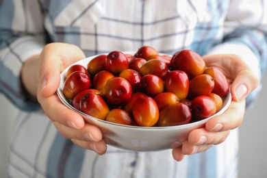 Photo of Woman holding bowl with palm oil fruits, closeup