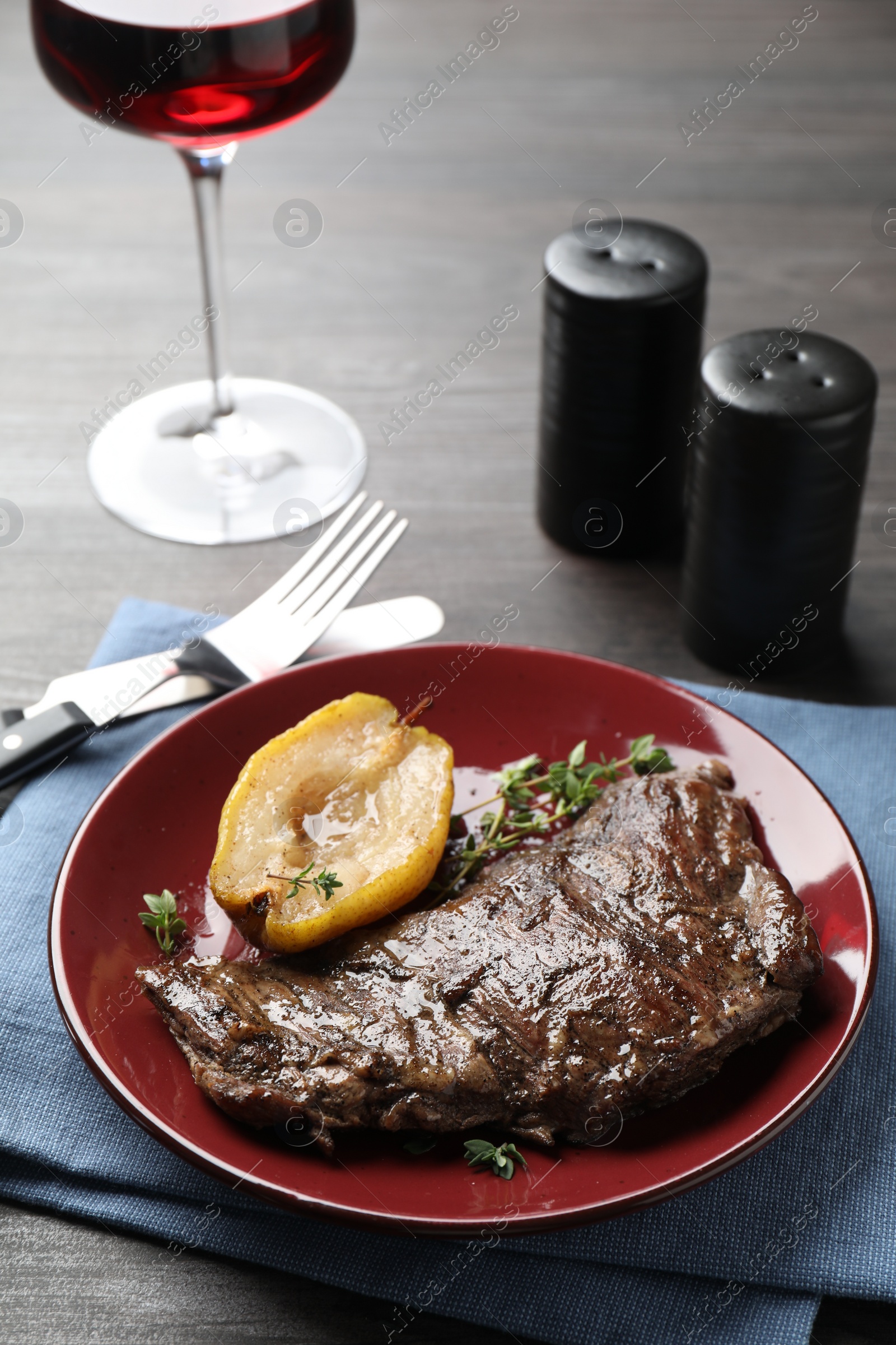 Photo of Delicious roasted beef meat and caramelized pear served on grey wooden table